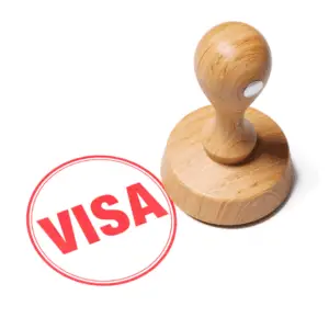 Wooden stamp beside red visa mark.