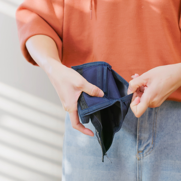 Person holding open empty wallet, wearing casual clothes.