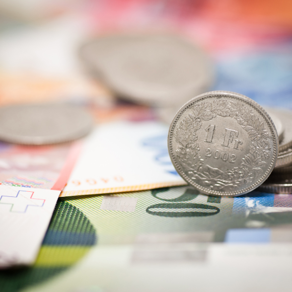 Swiss francs coins on colorful banknotes