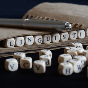 Linguistics spelled with letter dice and pen.