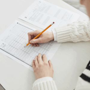 Person filling out scantron sheet with pencil.