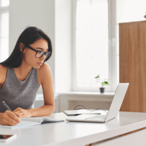 Woman working on laptop and taking notes.