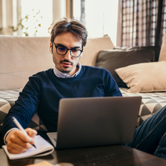 Man working on laptop and taking notes.